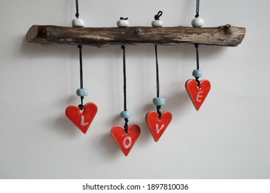 Red ceramic handmade heart pendants hanging on a rough gray branch on a white background. Inscription - Love. Valentine's Day gift               - Powered by Shutterstock