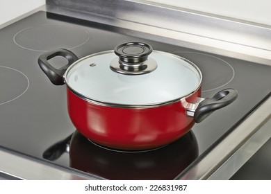 Red Ceramic Pan With Cover On Electric Hob In Modern And Domestic Kitchen, View From Above