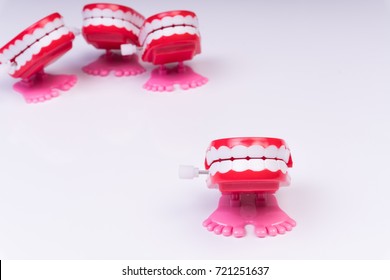 Red chattering teeth toy standing away from group. Isolated white backdrop.