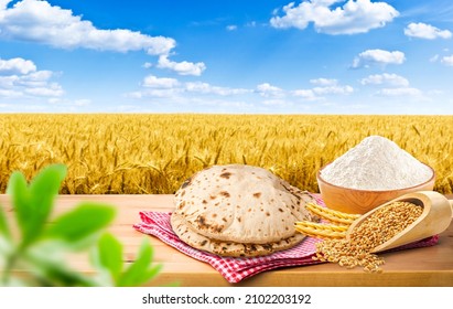 Red checked tablecloth on wood with wheat field, Wheat Flour or Atta, Roti, Fulka, Indian Bread, Flatbread, Whole Wheat Flat Bread, Chapathi, Wheaten Flat Bread, Chapatti, or Chappathi, wheat grains