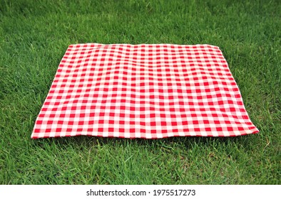 Red Checkered Gingham Cloth On Green Grass. Picnic Towel.Tabletop Advertisement Design. Food Promotion Display. Laying Napkin.