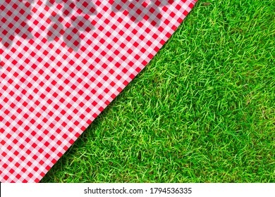 Red checkered table cloth on green turf or grass from top view. - Powered by Shutterstock