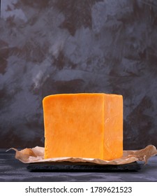 Red Cheddar Cheese Block Against The Grey Background