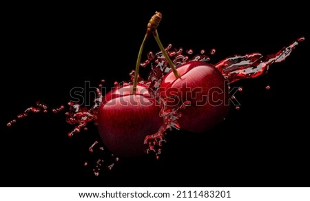 red cherries in red juice splash on a black background