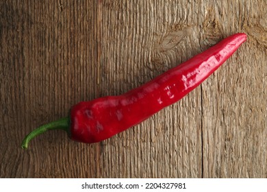 Red Chile Pepper On Rough Wooden Background Texture.