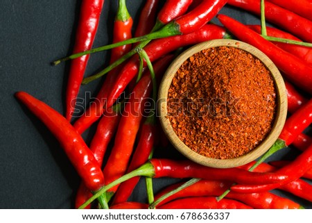 Red chili peppers and chili flakes on black background