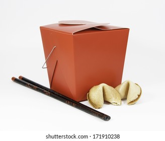 Red Chinese Takeout Box, Black And Red Wooden Chopsticks, And Two Fortune Cookies Against A White Background