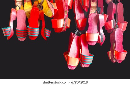 Red Chinese Wooden Clogs Hanging On A Black Wall