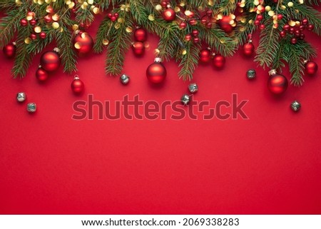 Red Christmas background with fir branches, lights and decorations .