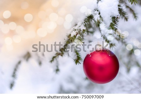 Red christmas ball hanging on pine branches covered with snow. Shine and glowing effect
