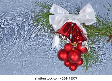 Red Christmas Bells And Christmas Balls With White Bow Against A  Window Frost Background.