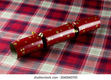 Red Christmas Cracker On A Tartan Plaid Table Cover