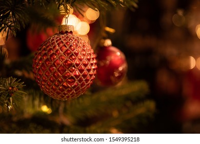 red christmas decoration on a christmastree with lights in the background