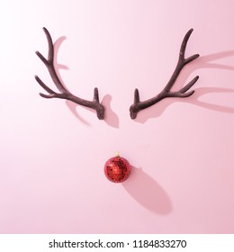 Red Christmas Disco Ball Bauble With Reindeer Antlers On Pink Background. Minimal New Year Santa Concept. Flat Lay.