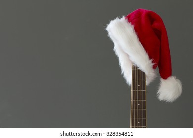 Red Christmas Hat On Guitar With Grey Background, Merry Christmas Song