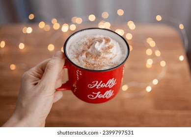 Red Christmas mug with cocoa and whipped cream in a girl's hand - Powered by Shutterstock