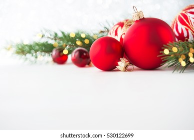 Red christmas ornaments on white background with xmas tree, twinkle bokeh lights. Merry christmas card. Winter holiday xmas theme. Happy New Year. Space for text. - Powered by Shutterstock