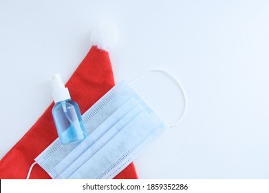 Red Christmas Santa Hat Medical Protective Mask And Hand Sanitizer On White Background.