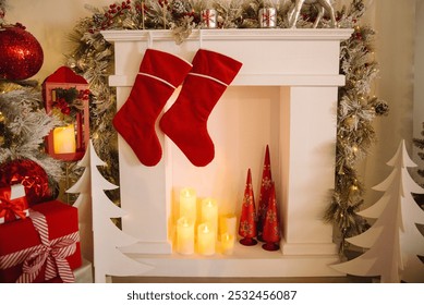 Red Christmas stockings hang on a white mantel above glowing candles and holiday decorations, creating a cozy festive scene. - Powered by Shutterstock