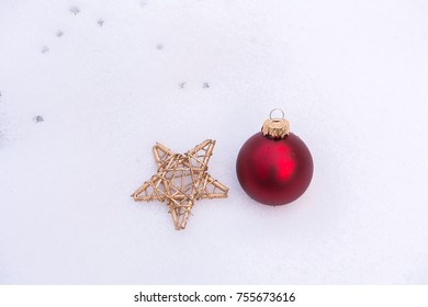 Red christmasball and golden star in textured snow
