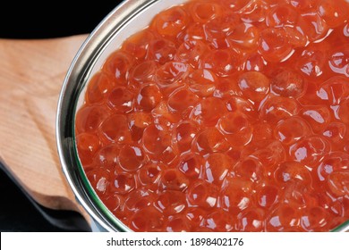 Red Chum Salmon Caviar Lies In A Tin Can On A Wooden Stand On A Black Background Close-up Macro Photography