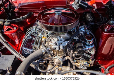 red classic muscle car under the hood, v8 engine with big chromed round air intake filter, tubes, wires, pipes, mechanical and electrical other parts