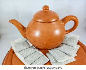 Red Clay Teapot And Stack Of Tea Bags On A Red Clay Tray On A White Background