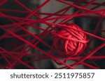 A red clew of thread as a web. Art of knitting. Concept of intricacy and complexity of life. Threads of fate and their interweaving. Difficulties in job. Wool yarn. Cotton cord. Textured background.