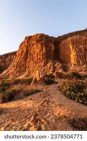 Red cliffs on the sandy beach in Algrave, Portugal at sunset