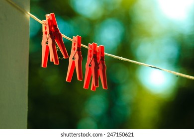 Red clips for washing laundry clothes pegs on string rope outdoor. Housework concept.