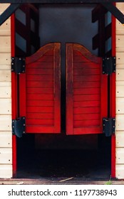 Red Closed Western Saloon Doors On A White Wooden Wall On A Bright Sunny Day