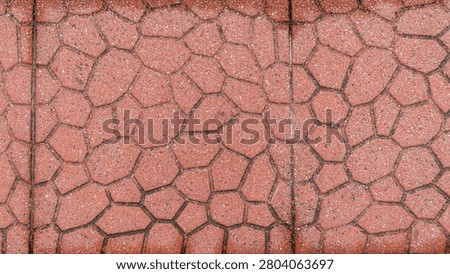 Red cobblestone patterned road pavement surface with a seam line, an outdoor ground texture.