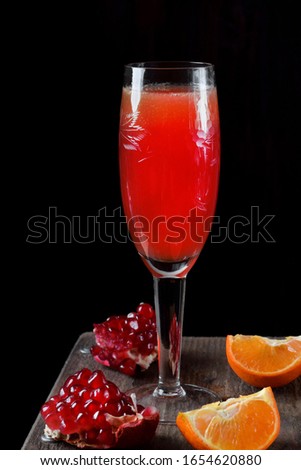 Red cocktail with champagne and fruit syrup in a champagne glass against the black background
