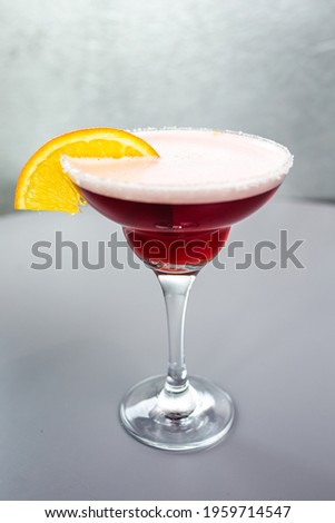 red cocktail with orange on a gray background.