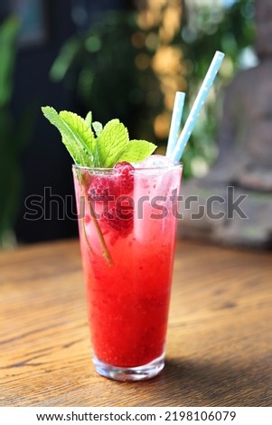 Red cocktail, raspberry mojito, a long drink in a glass, with ice cubes, rasberries and mint leaves, on a black stone background, selective focus.
