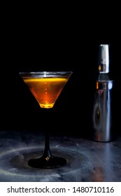 Red Cocktail And Cocktail Shaker On Black Background With Overhead Light 