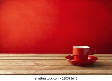 Red Coffee Cup On Wooden Table Over Red Grunge Background