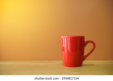 Red Coffee Cup On Wooden Desk With Brown Background 