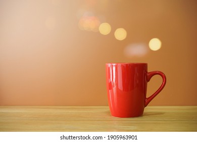 Red Coffee Cup On Wooden Desk On Brown Background With Bokeh