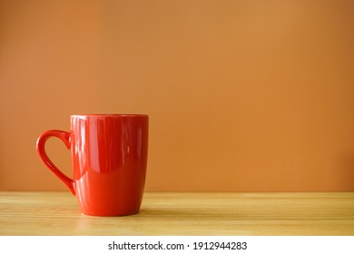 Red Coffee Cup On Wooden Desk With Brown Background 