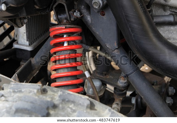 Red coil spring stands out among quad bike\
suspension parts