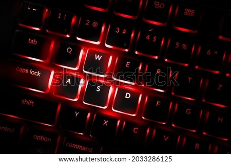 Red color backlighted computer keyboard. Close-up of highlighted default keys in games associated with movements. Professional computer game playing, esport business and online world concept.