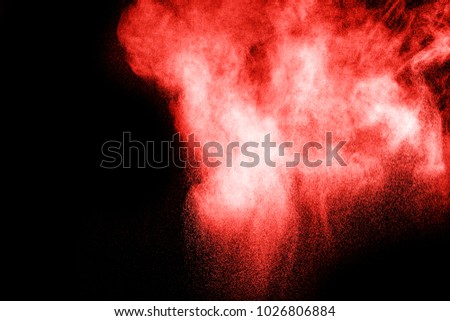 red color powder explosion on black background. Mauve red color cloud. red dust splash in the air. Freeze motion red color paint Holi.