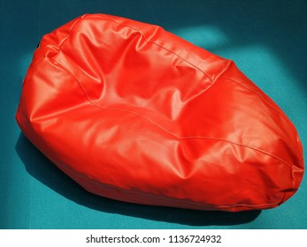 Red Colored Bean Bag Seat On Blue Background In Direct Sunlight