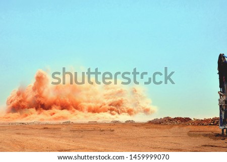 Red colored dust clouds and particles after the industrial detonator blast 