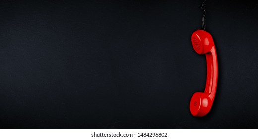 red  colored old fashioned retro phone reciever with black telephone wire on dark slate blackboard background with copy space. business communication support service problem and solution concept