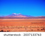 Red colorful desert against the background of purple and violet mountains covered with snow and blue sky. Amazing nature scenery near Tehran - Isfahan road, Iran, Middle East, Western Asia.
