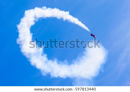 Red combat fighter with white circle smoke behind in the blue sky.