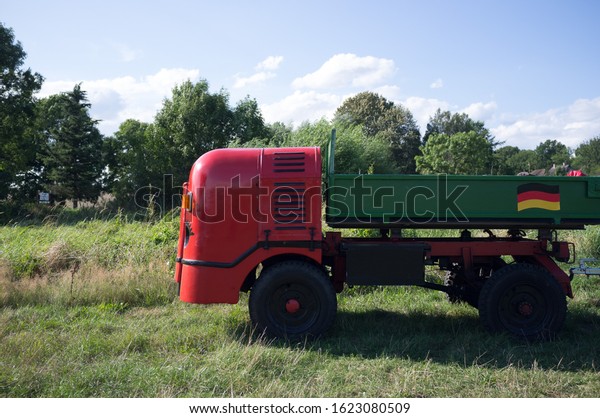 Red commercial vehicle in\
a meadow
