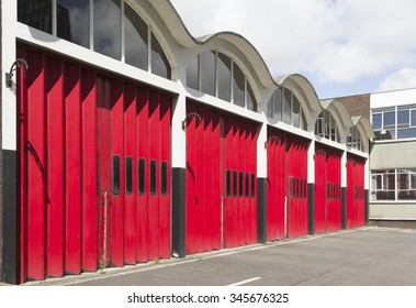Red concertina-type folding garage doors at a redundant fire station in England